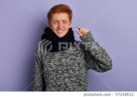 Cheerful excited young man standing and holding capsule Cheerful excited young man standing and holding capsule 57248632