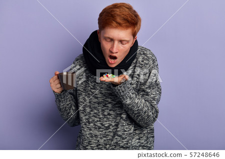 unhappy young man holding many colorful capsuls on palm 57248646