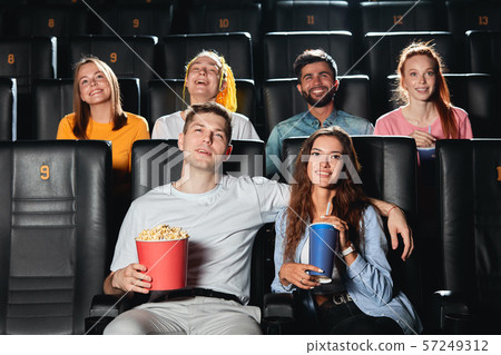 Happy couple eating popcorn , drinking cola while watching film 57249312