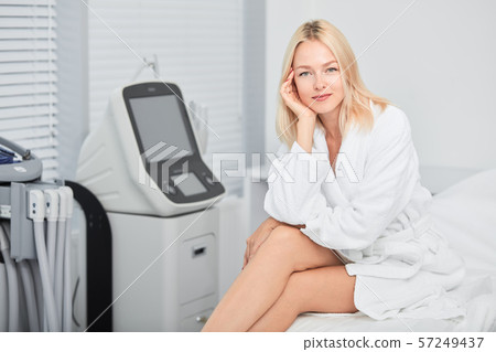 good looking positive girl with palm on her cheek sitting with crossed legs 57249437