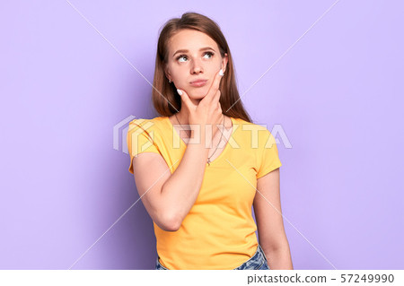 Unsure pretty young lady full of doubts, holding chin, looking right thoughtfully 57249990