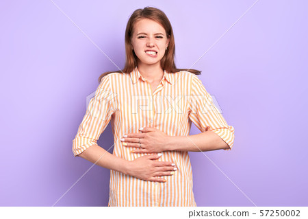 Female student holding with both hands her belly, suffers from pain in stomach 57250002