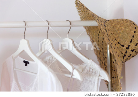 Clothing from eco organic cotton in trend colors and accessories hang on a hanger near a white wall Clothing from eco organic cotton in trend colors and accessories hang on a hanger near a white wall 57252880