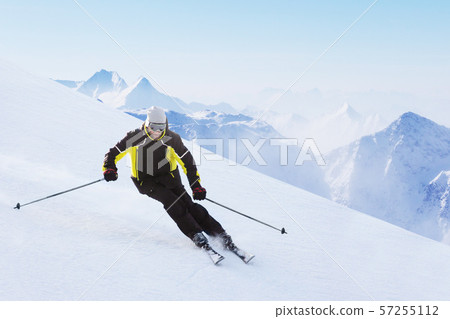 Alpine skier on piste running downhill 57255112