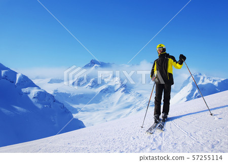 Skier standing on mountain slope Skier standing on mountain slope 57255114