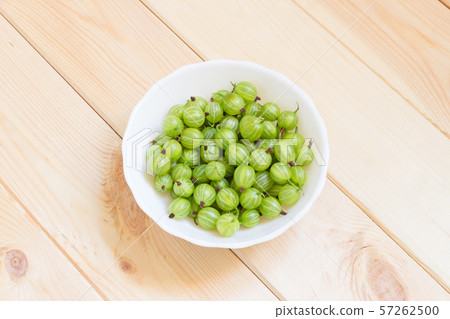 Summer harvest of gooseberries, green berries in a white bowl on wooden table Summer harvest of gooseberries, green berries in a white bowl on wooden table 57262500