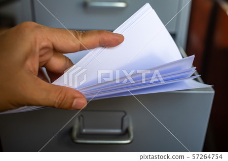 Woman's hand pick up white papers for write letter, Filing cabinet with open drawer, Grey silver metal colour, Administration and storage concept, closeup & Macro shot, Selective focus Woman's hand pick up white papers for write letter, Filing cabinet with open drawer, Grey silver metal colour, Administration and storage concept, closeup & Macro shot, Selective focus 57264754