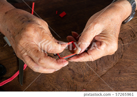 Senior man' s hands to provide Amulet, .Small Buddha image with a metal cap on wood table texture background , Close up & Macro shot, Asian body part, Craftsman processing concept Senior man' s hands to provide Amulet, .Small Buddha image with a metal cap on wood table texture background , Close up & Macro shot, Asian body part, Craftsman processing concept 57265961