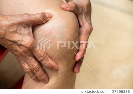 Senior woman suffering from knee pain sitting on chair, Massaging by her hand, Close up, Body concept Senior woman suffering from knee pain sitting on chair, Massaging by her hand, Close up, Body concept 57266288
