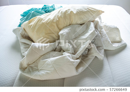 Turquoise and White crumpled bed sheet, Ivory pillow on white bed, Close up shot, Selective focus, Bedroom cleaning concept 57266649