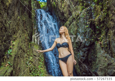 Young beautiful woman standing in the water at the waterfall 57267335