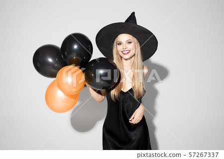 Young woman in hat as a witch on white background 57267337