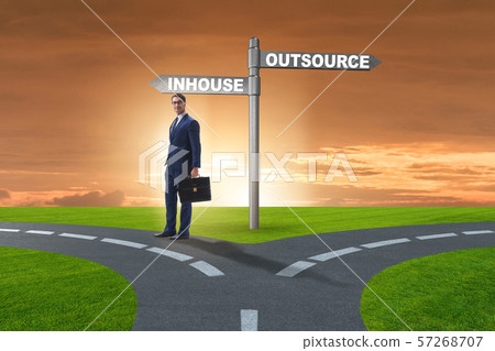 Businessman at crossroads deciding between outsourcing and inhou 57268707