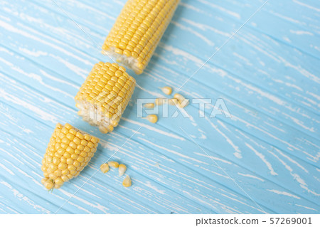 Corn cob with green leaves lies on table blue Corn cob with green leaves lies on table blue 57269001