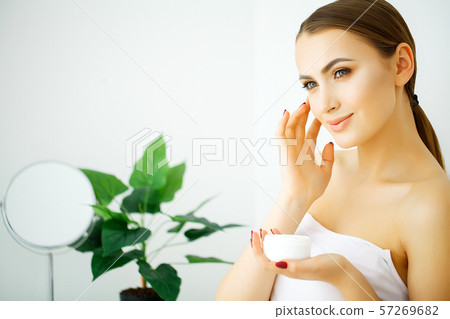 Beautiful model applying cosmetic cream treatmen on her face Beautiful model applying cosmetic cream treatmen on her face 57269682