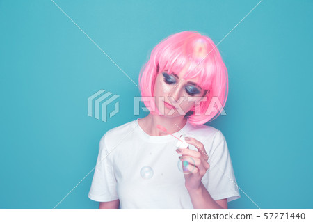 Happy woman blowing soap bubble in a blue studio. Happy woman blowing soap bubble in a blue studio. 57271440