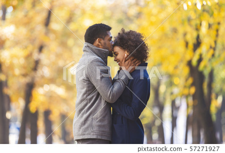 Afro man kissing his girlfriend forehead while walking Afro man kissing his girlfriend forehead while walking 57271927