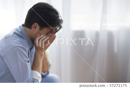 Frustrated Lonely Man Covering Face With Hands Sitting Against Window Frustrated Lonely Man Covering Face With Hands Sitting Against Window 57272175