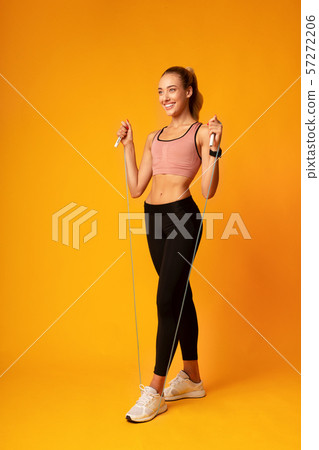 Girl Doing Jump Rope Workout Over Yellow Background 57272206