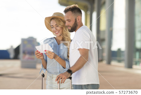Happy couple looking at boarding pass checking departure time Happy couple looking at boarding pass checking departure time 57273670
