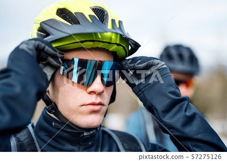 Two mountain bikers standing on road outdoors in winter. 57275126
