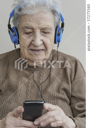 senior woman listening music with headphones and senior woman listening music with headphones and 57275560