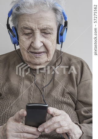 Senior woman listening music with headphones and 57275562