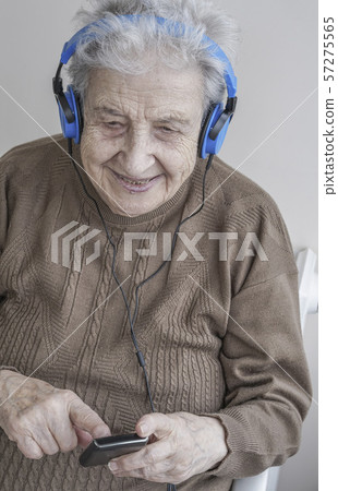 Senior woman listening music with headphones and 57275565