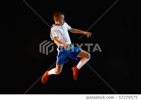 Young boy as a soccer or football player on dark studio background Young boy as a soccer or football player on dark studio background 57279575