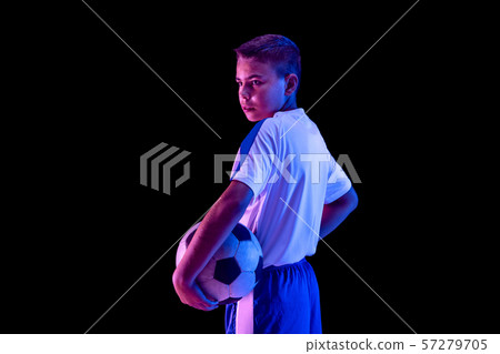 Young boy as a soccer or football player on dark studio background Young boy as a soccer or football player on dark studio background 57279705