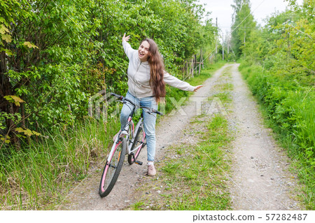 Young woman riding bicycle in summer city park outdoors. Active people. Hipster girl relax and rider 57282487