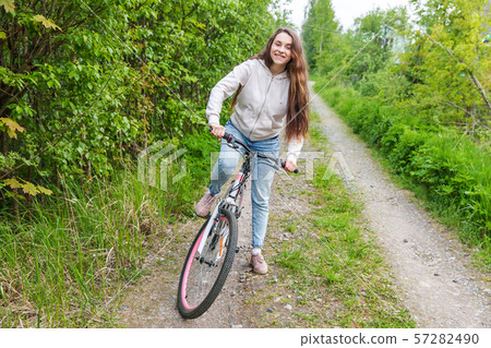Young woman riding bicycle in summer city park outdoors. Active people. Hipster girl relax and rider 57282490