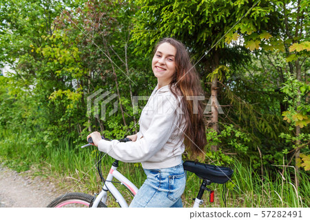 Young woman riding bicycle in summer city park outdoors. Active people. Hipster girl relax and rider 57282491