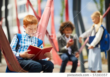 Schoolboy with book in the park 57283357