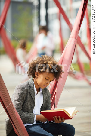 Schoolboy with book outdoors 57283374
