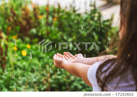 Girl's hands catching raindrops on blurred green 57283602