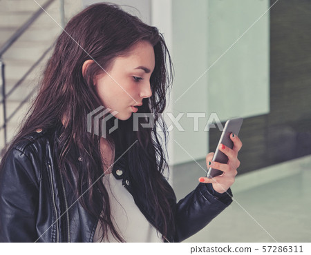 Calm woman using cellphone indoors. Calm woman using cellphone indoors. 57286311