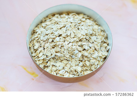 Uncooked oatmeal or oat flakes in a bowl 57286362