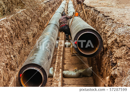 One worker is using circular welding machine on hot water pipes on the side of the road One worker is using circular welding machine on hot water pipes on the side of the road 57287599