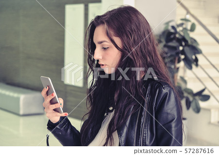 Fashion portrait of pretty woman with smartphone against the office building interier Fashion portrait of pretty woman with smartphone against the office building interier 57287616