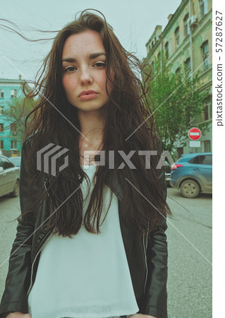 Peaceful looking girl posing with windy hair ouside, wide angle smartphone lens imitation vertical Peaceful looking girl posing with windy hair ouside, wide angle smartphone lens imitation vertical 57287627