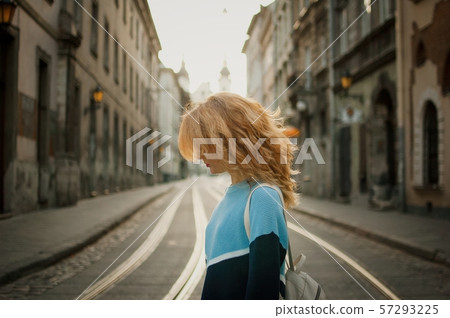 Side view of beautiful young adult girl tourist enjoying her trip early in the morning in empty city Side view of beautiful young adult girl tourist enjoying her trip early in the morning in empty city 57293225