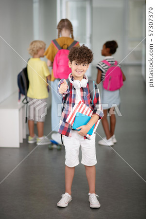 Curly dark-haired boy feeling positive at school Curly dark-haired boy feeling positive at school 57307379