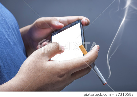 Man smoking cigarette while holding mobile phone Man smoking cigarette while holding mobile phone 57310592