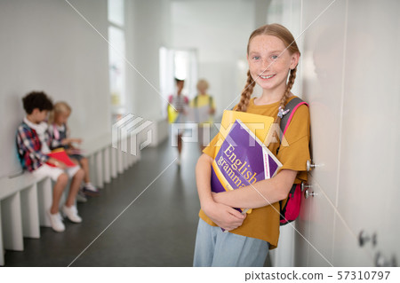 Beautiful schoolgirl holding boy while standing near locker Beautiful schoolgirl holding boy while standing near locker 57310797