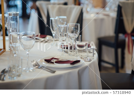 Glasses, flower fork, knife served for dinner in restaurant with cozy interior Glasses, flower fork, knife served for dinner in restaurant with cozy interior 57318940