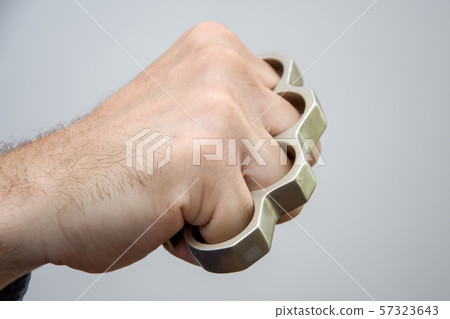 Man strikes brass knuckles on a light background, a prohibited weapon in a fight 1 57323643