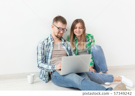Charming young positive couple in casual clothes looking for an interior designer for their new Charming young positive couple in casual clothes looking for an interior designer for their new 57349242