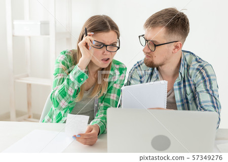 Upset husband and wife consider the total costs of payments and purchases made over the past month Upset husband and wife consider the total costs of payments and purchases made over the past month 57349276