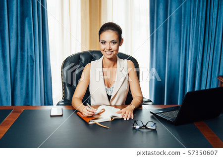Very beautiful business woman sits in an office chair and plans her business for the future 57350607
